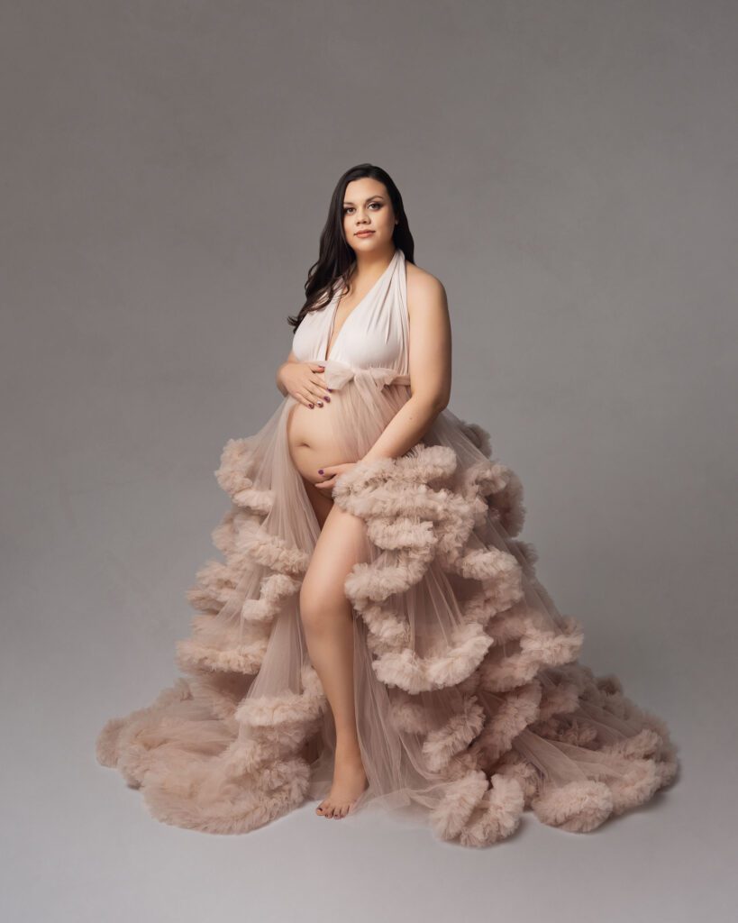 Studio maternity portrait in a flowing ruffle gown