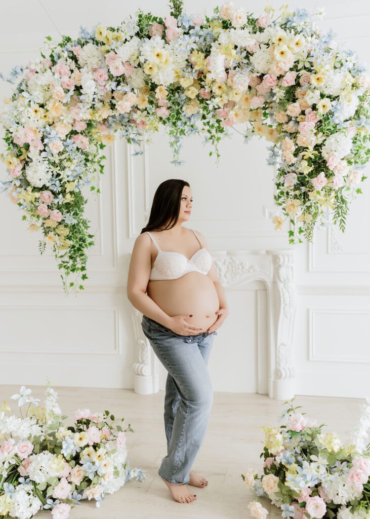 Elegant maternity photo under a floral arch in a Winnipeg studio